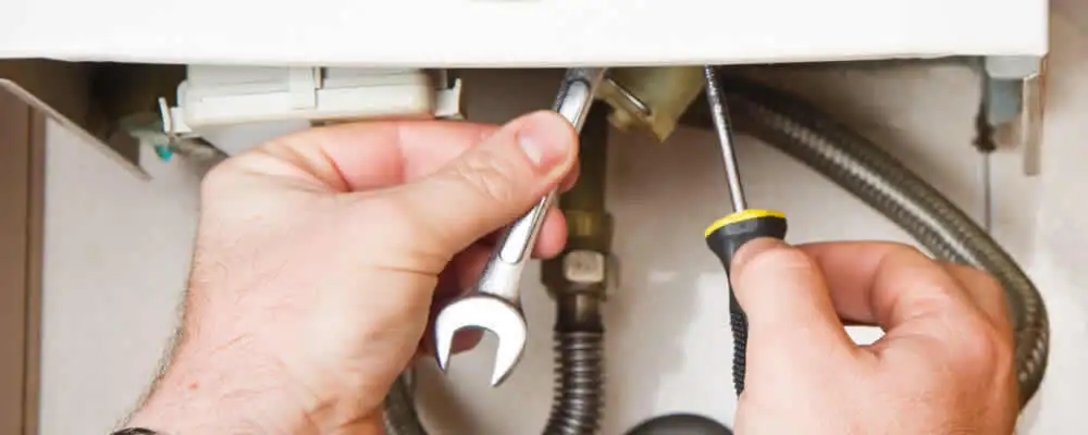Boiler repair technician tightening pipe fittings and connections in Boston, MA