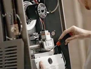 Furnace repair technician inspecting internal components and wiring in Boston, MA