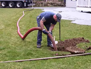 Septic pumping technician servicing a residential septic tank with a vacuum hose in Boston, MA