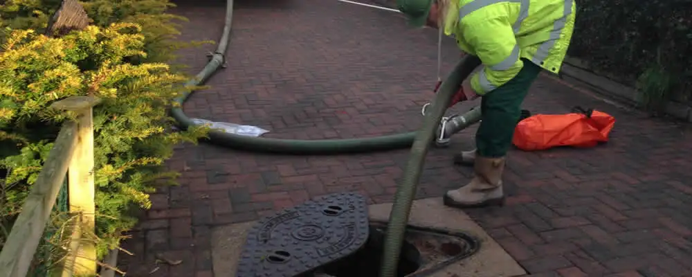 Septic tank cleaning technician servicing a septic tank with a vacuum hose in Boston, MA
