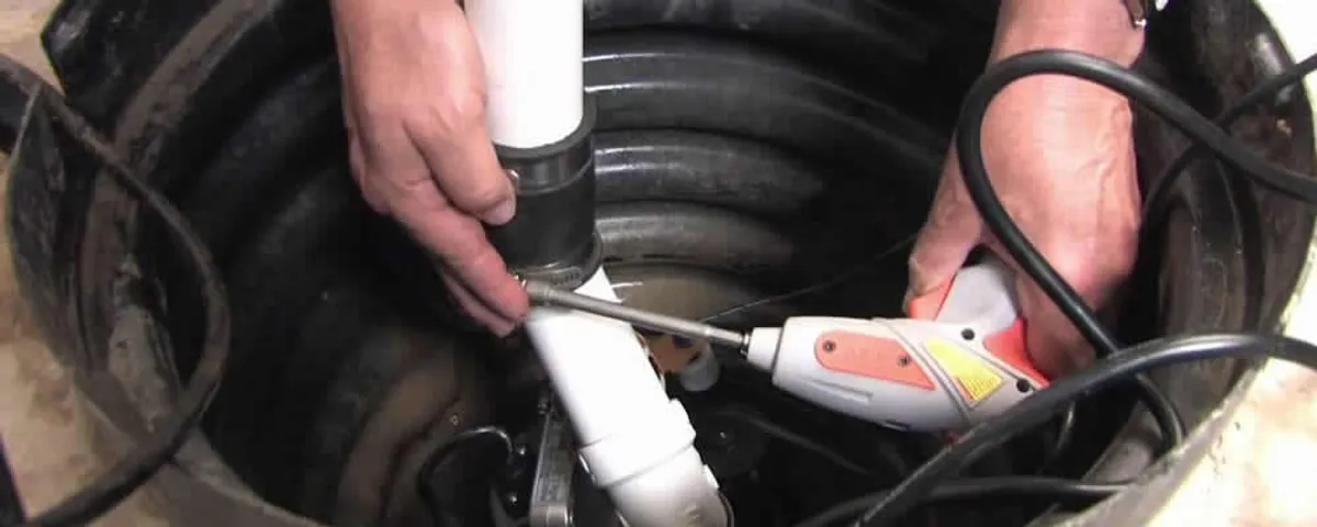 Sump pump installation technician connecting PVC discharge piping in Boston, MA
