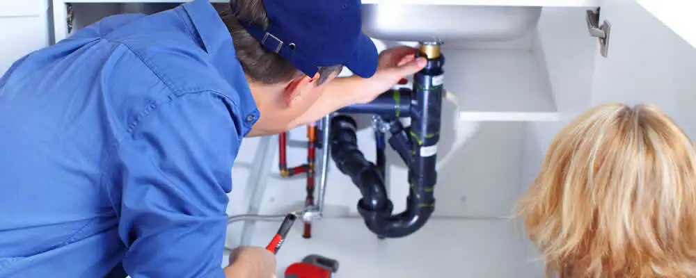 Plumber repairing under-sink drain pipes and fittings in Boston, MA