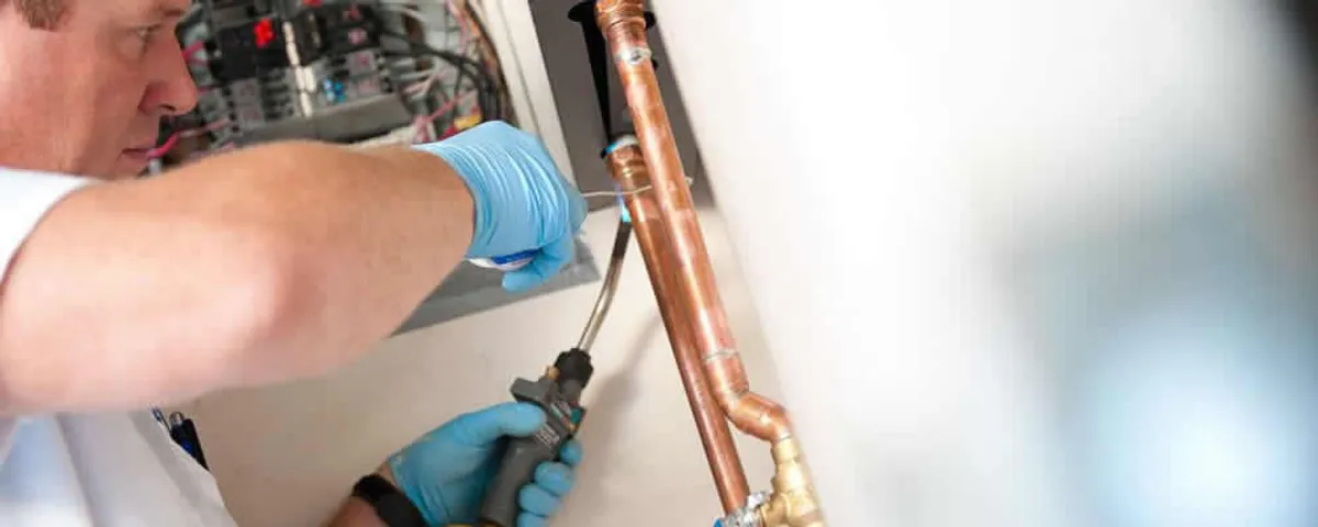 Water heater repair technician testing copper pipe connections and controls in Boston, MA